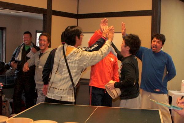 卓球台の端でハイタッチをしている男性の写真